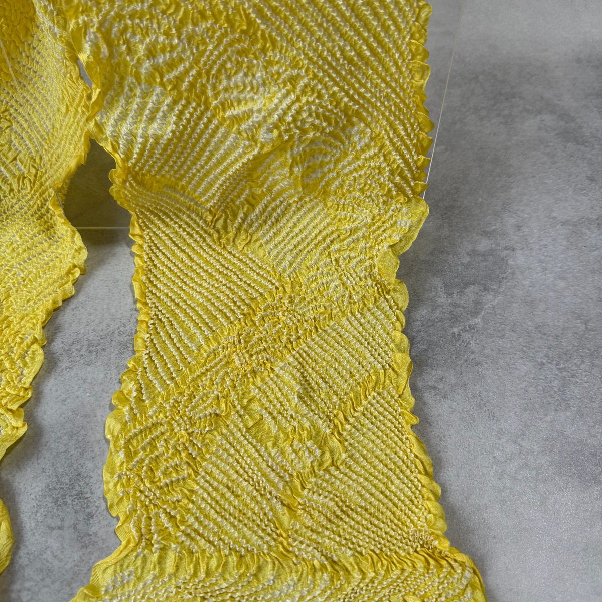 Close-up of large white floral shibori motifs on bright yellow silk