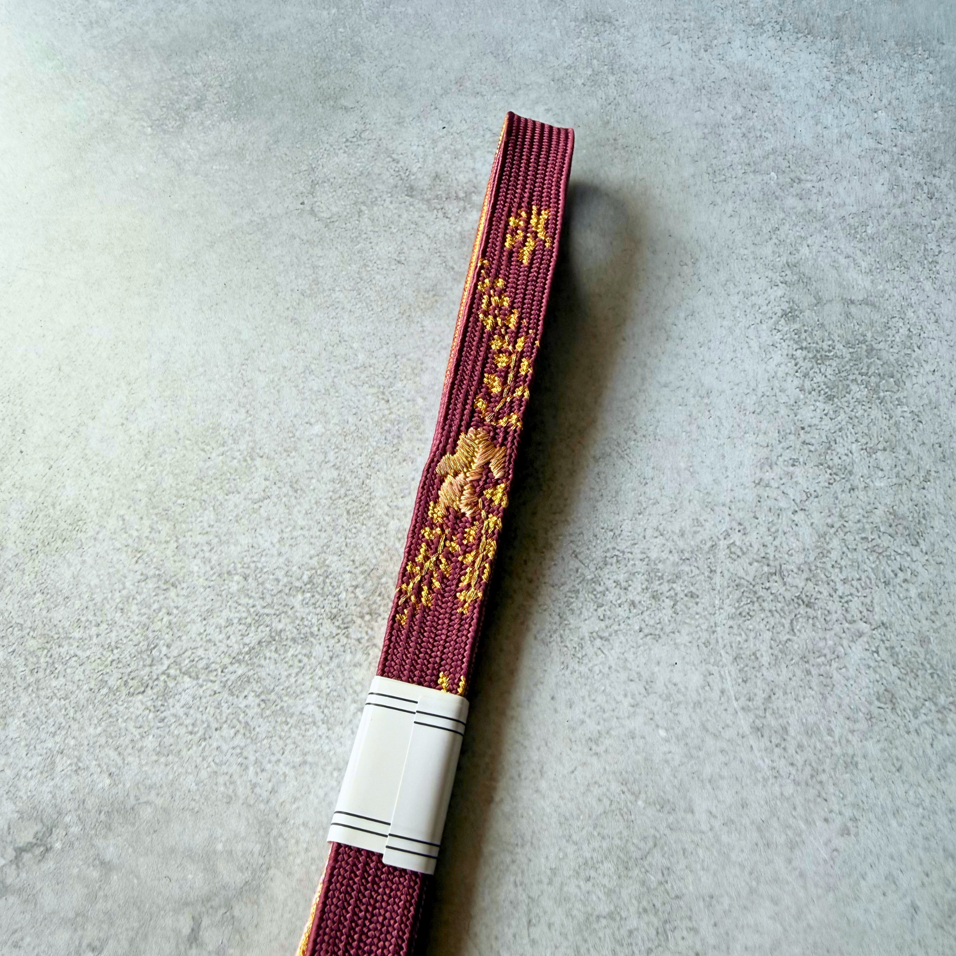 Detail of the burgundy and gold patterned side of the Japanese silk obijime cord