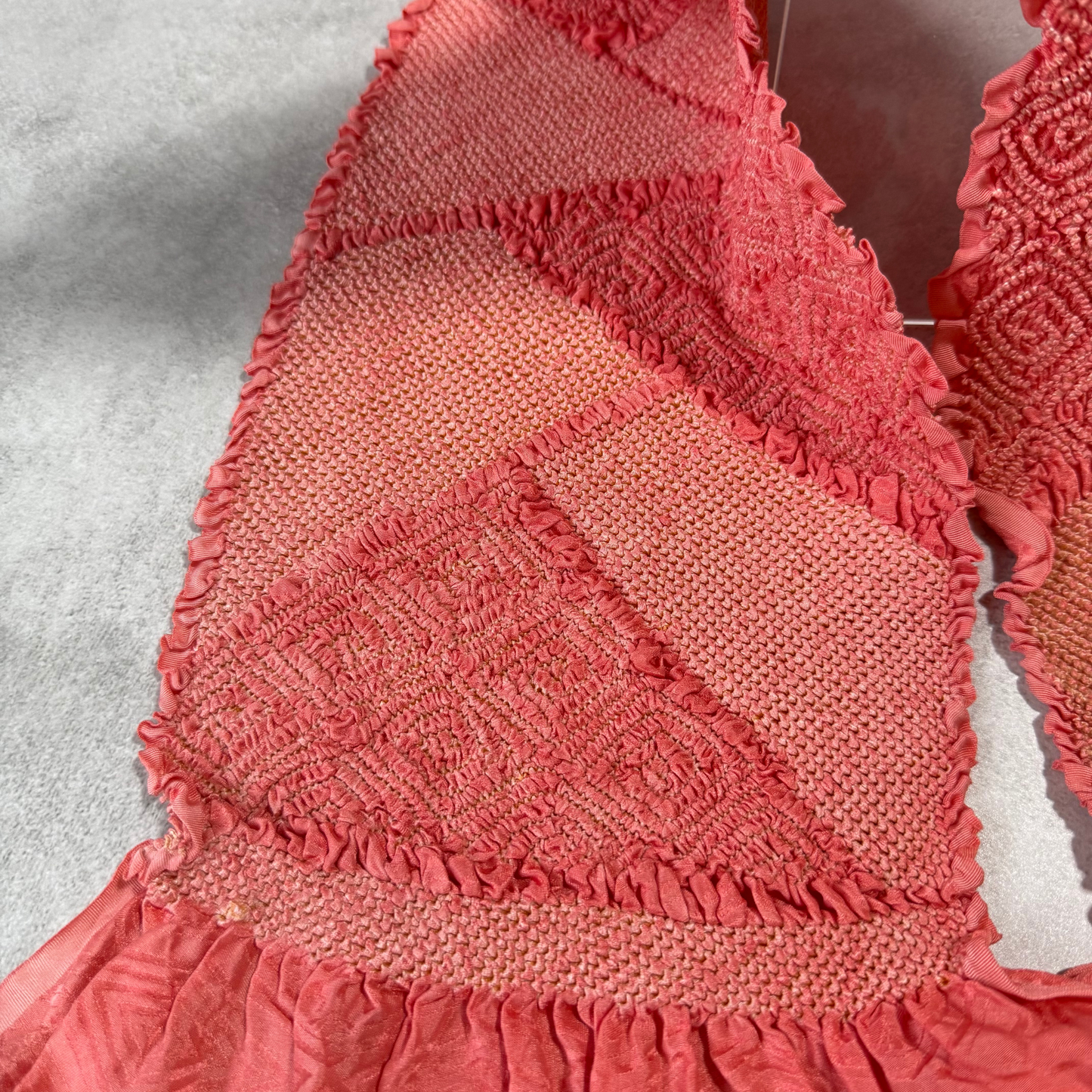 Close-up of textured geometric shibori sections and colour variation on coral pink obiage