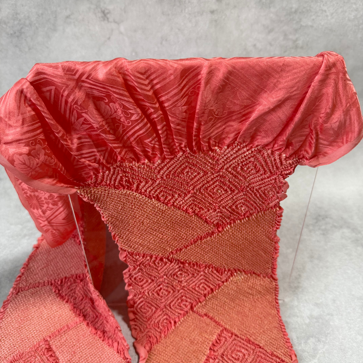 Close-up of woven floral and geometric pattern on coral pink Japanese silk obiage