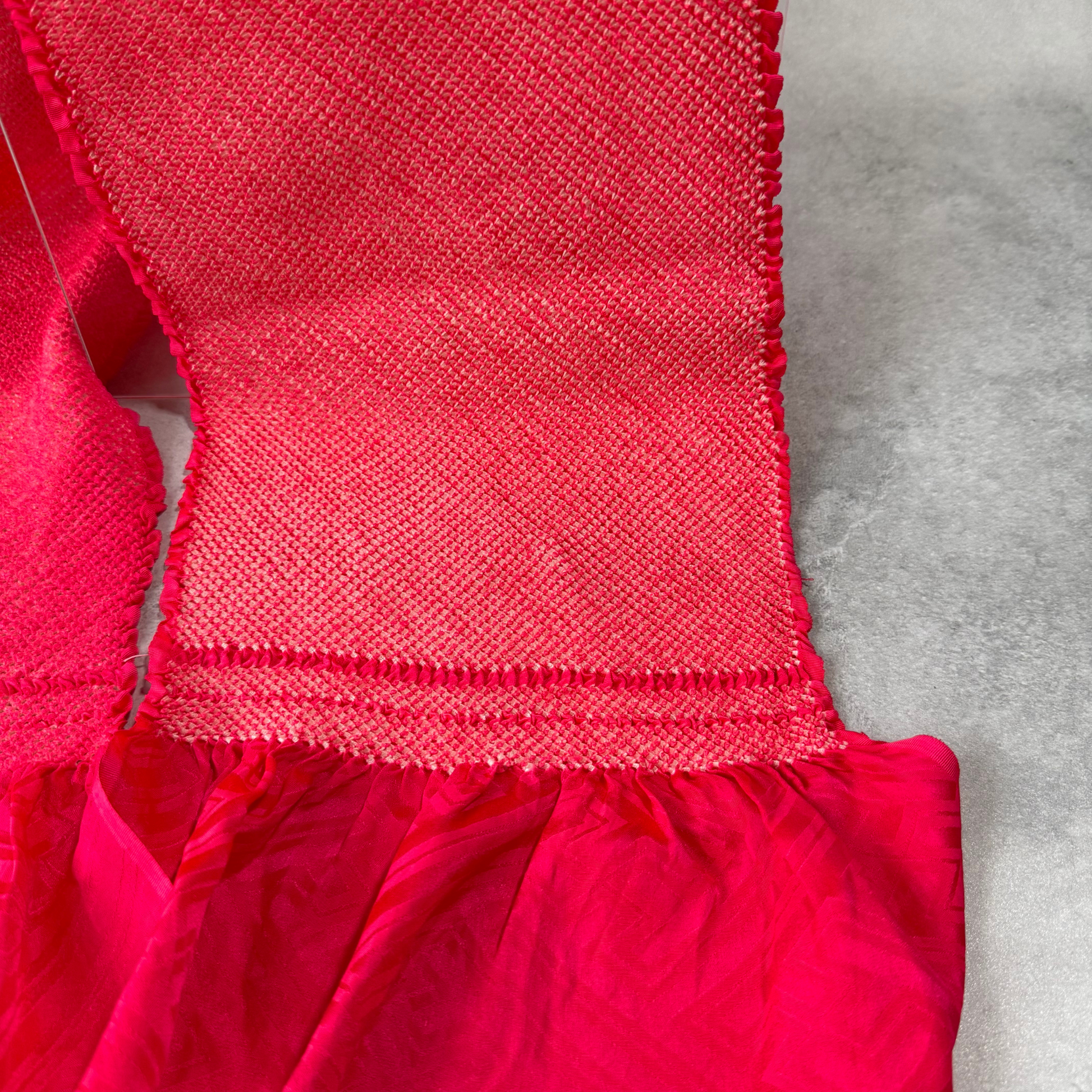 Close-up of dense kanoko-style shibori texture on a vivid fuchsia pink furisode obiage