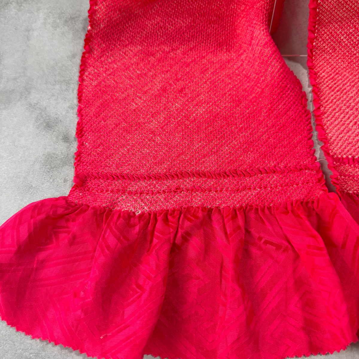 Detailed view of the shibori edge and geometric woven pattern on fuchsia silk