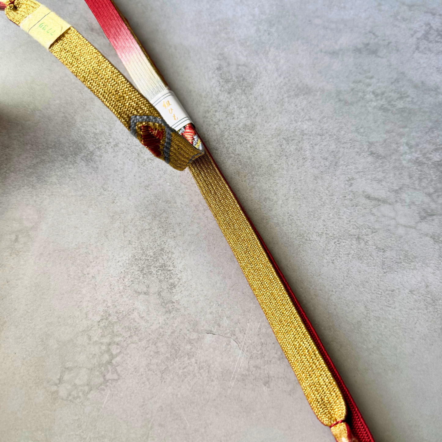 Detailed view of the gold and red reverse sections and braided construction of the Japanese obijime cord.