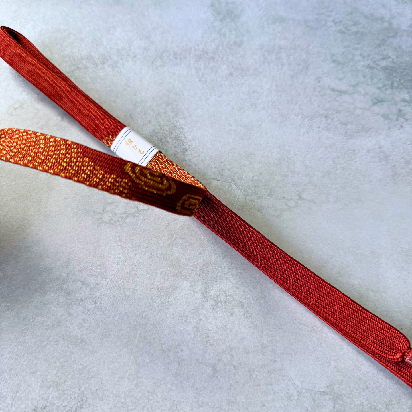 Detailed comparison of the gold patterned and vermilion red sides of a Japanese kumihimo obijime