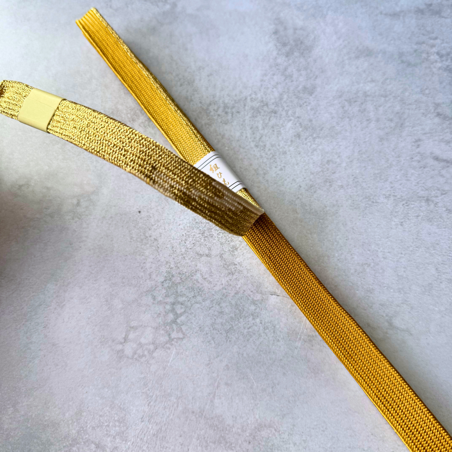 Detail comparing both sides and braided texture of the golden ochre and metallic gold silk obijime