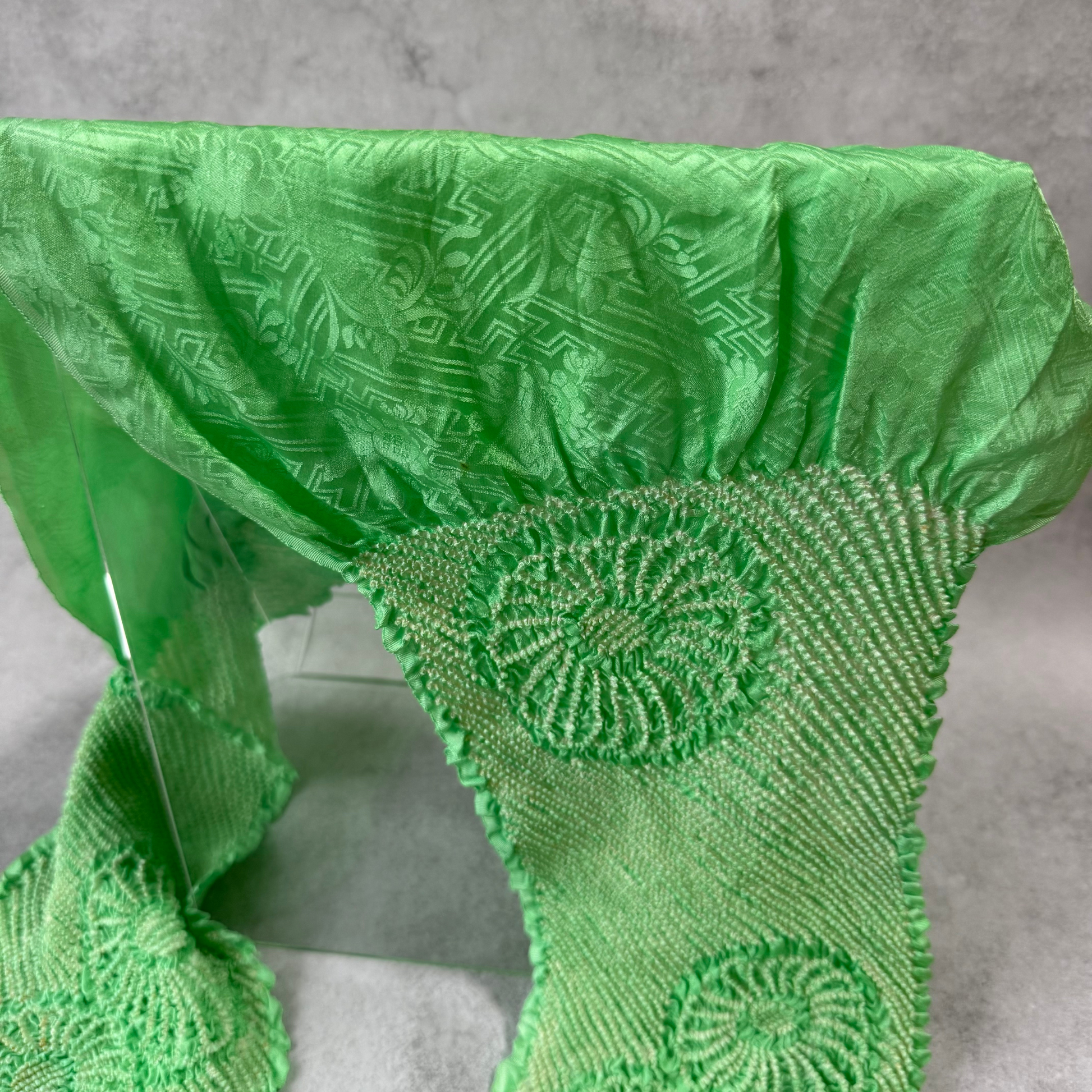 Close-up of floral and geometric jacquard patterns woven into bright green silk