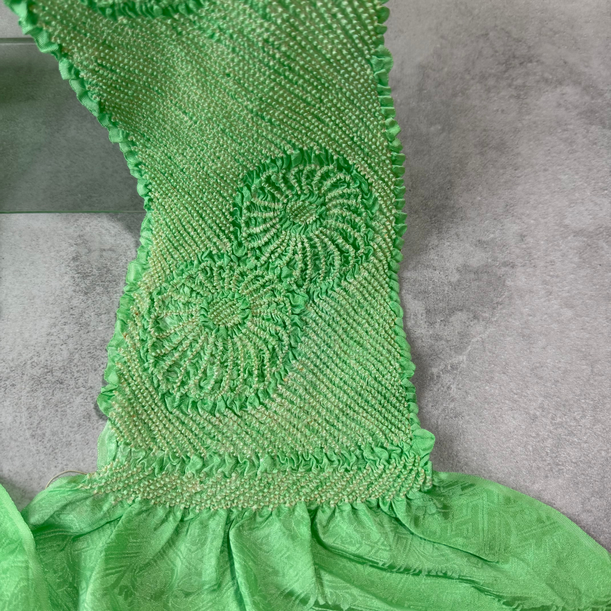 Detailed view of the textured shibori work on a vintage bright green Japanese obiage