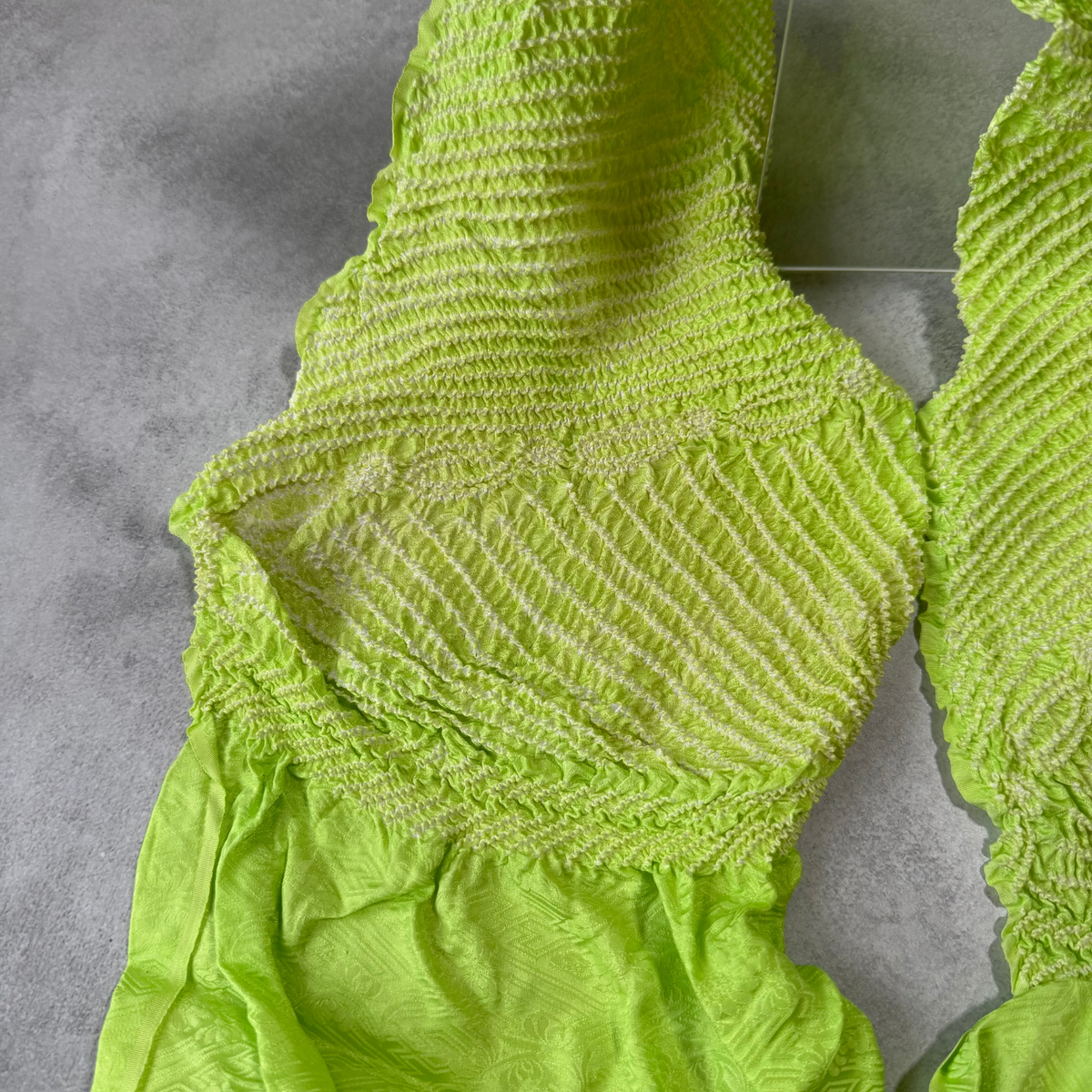 Detailed view of white shibori lines and floral designs on bright green silk