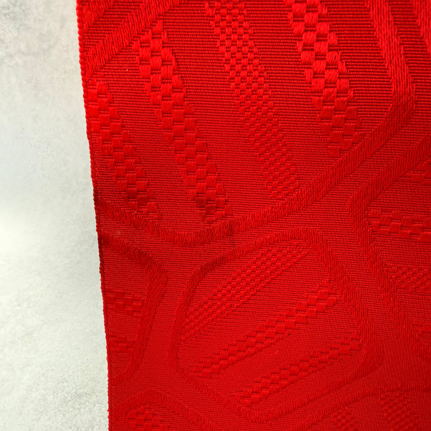 Edge and geometric weave detail of pre-owned red obi textile