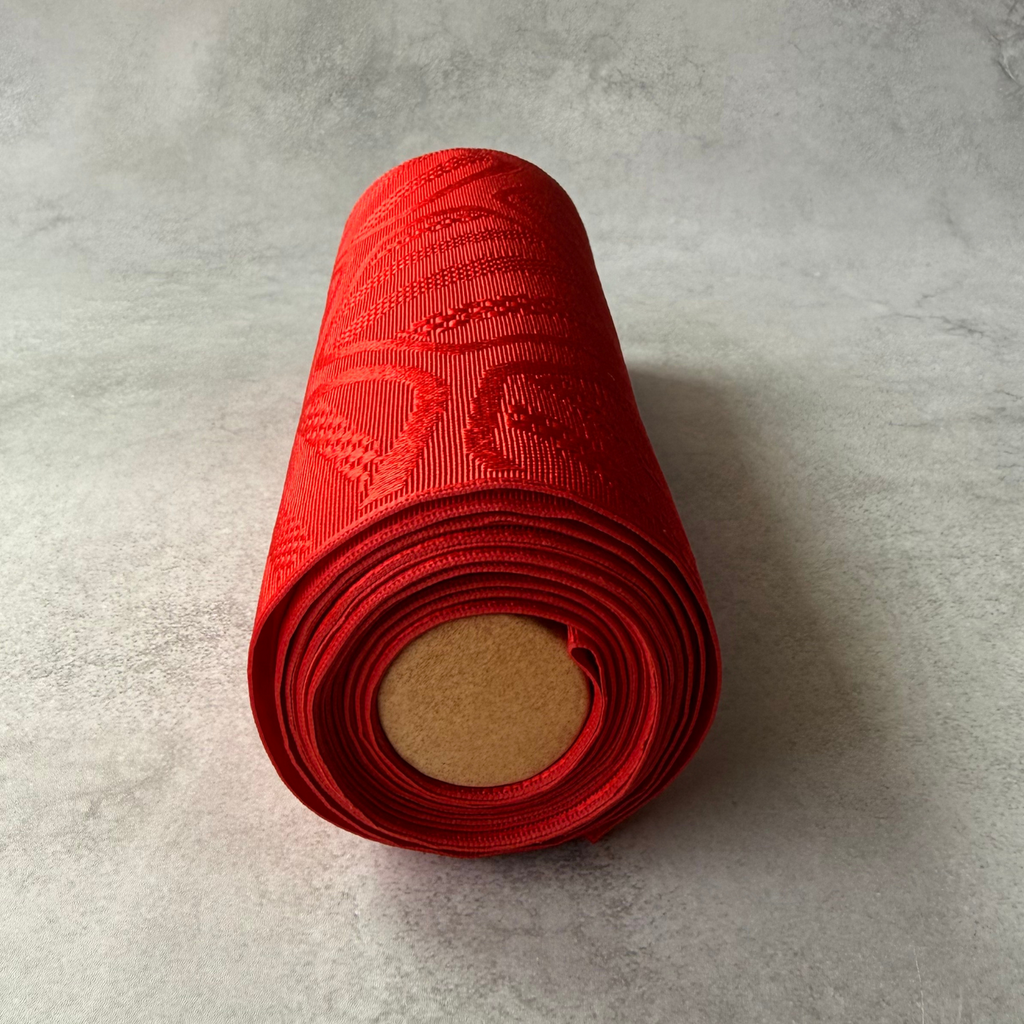 End view of rolled red Japanese obi fabric bolt
