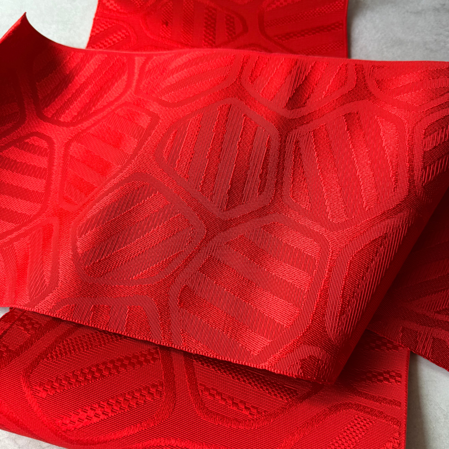 Red rayon obi fabric showing dimensional woven texture and sheen