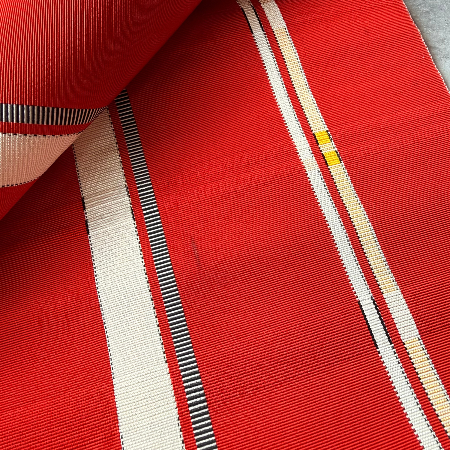 Close-up of red white black and yellow striped obi fabric