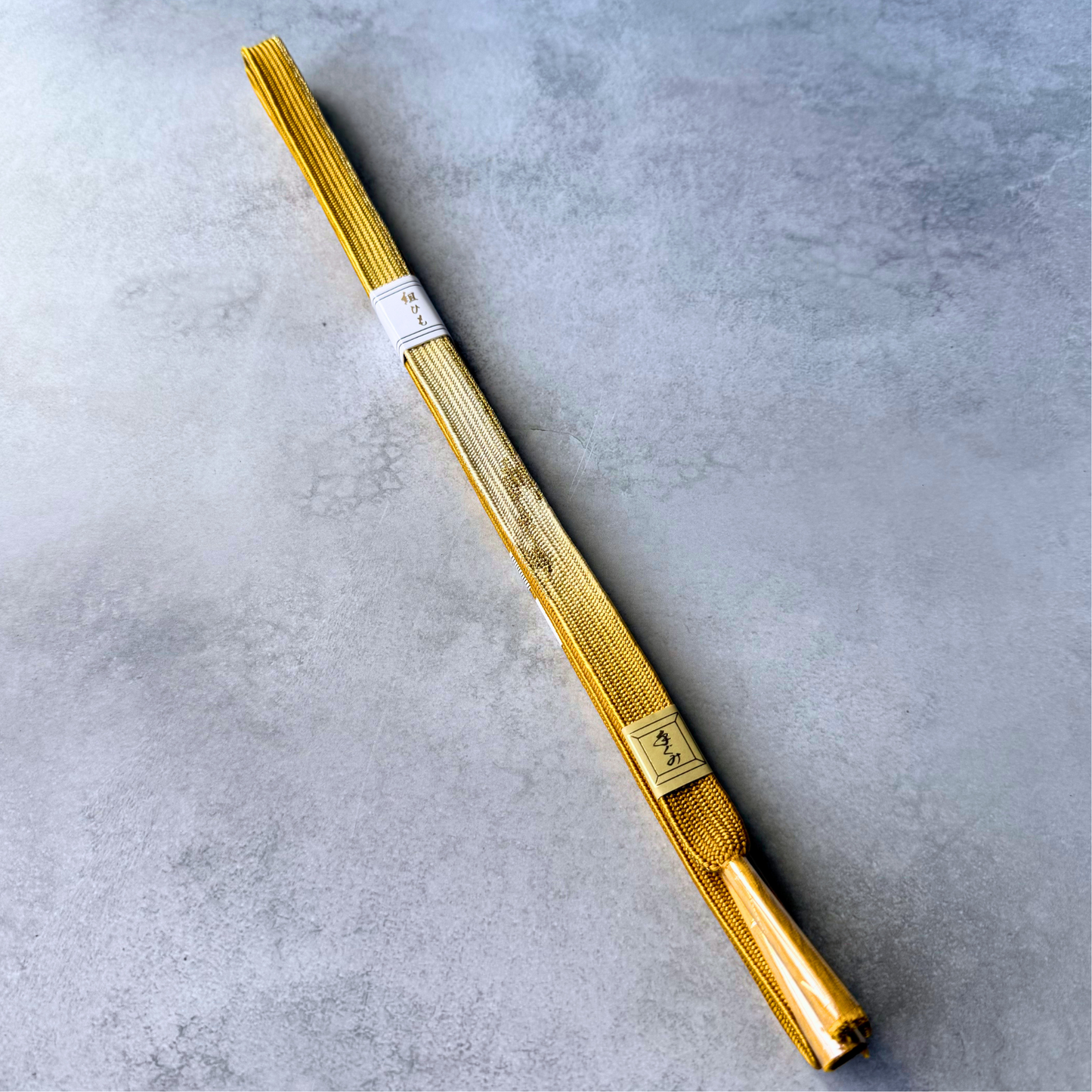 Full view of an unused Japanese silk Korai-gumi obijime cord in golden ochre and metallic gold