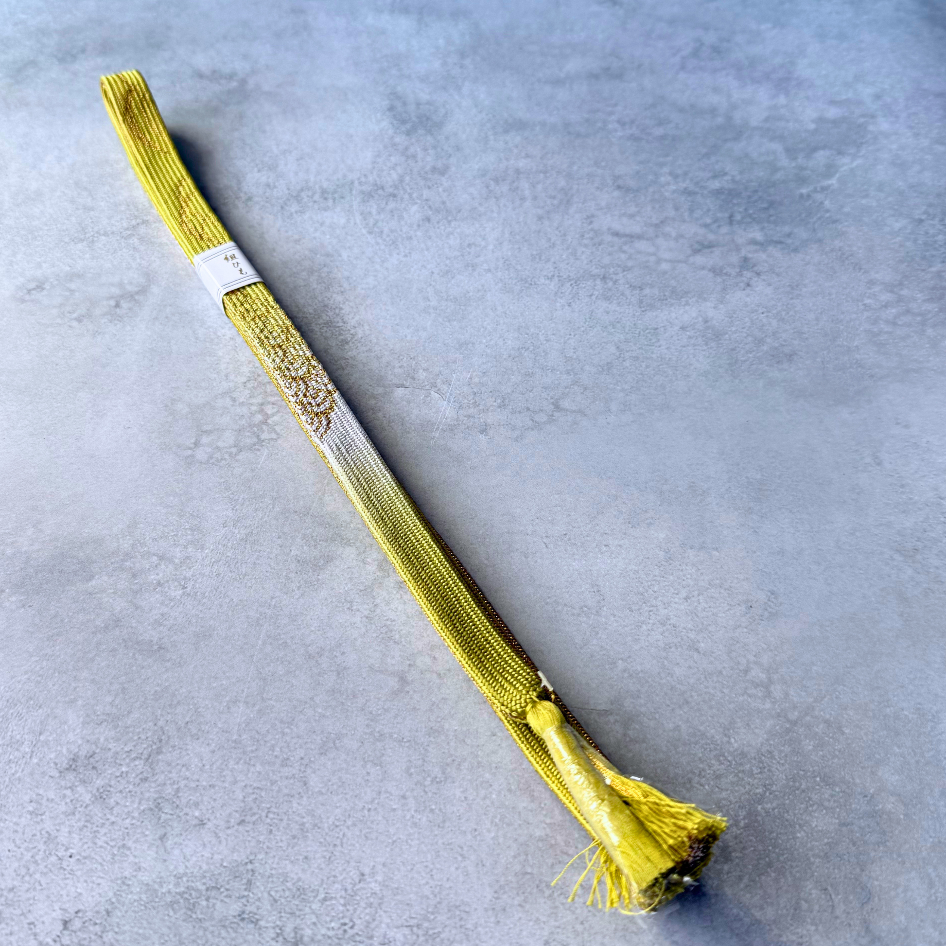 Full view of an unused Japanese silk Korai-gumi obijime in olive yellow, white and gold