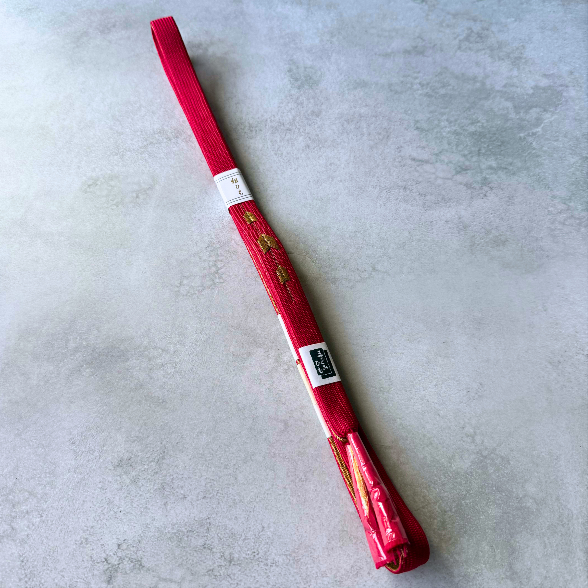 Full view of an unused Japanese silk Korai-gumi obijime cord in vivid crimson red and metallic gold