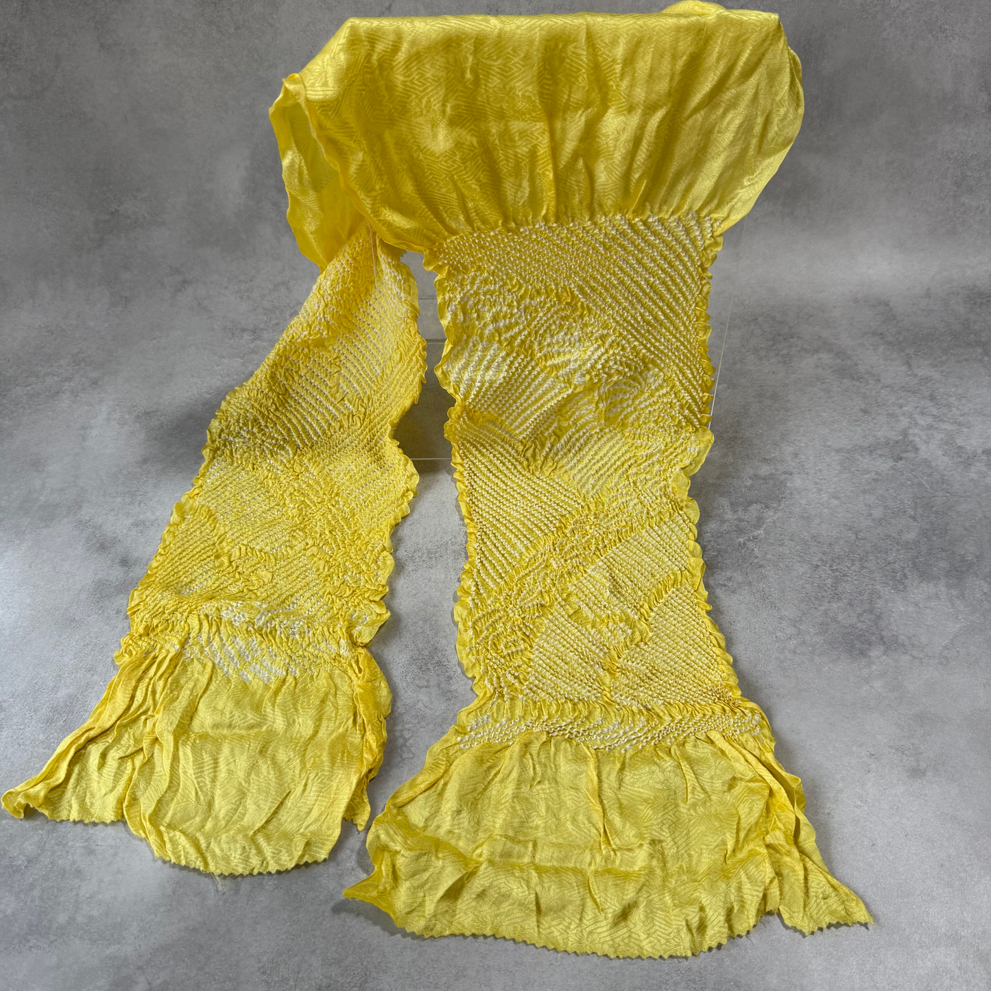 Full view of a vintage Japanese silk shibori obiage in bright yellow with white floral motifs