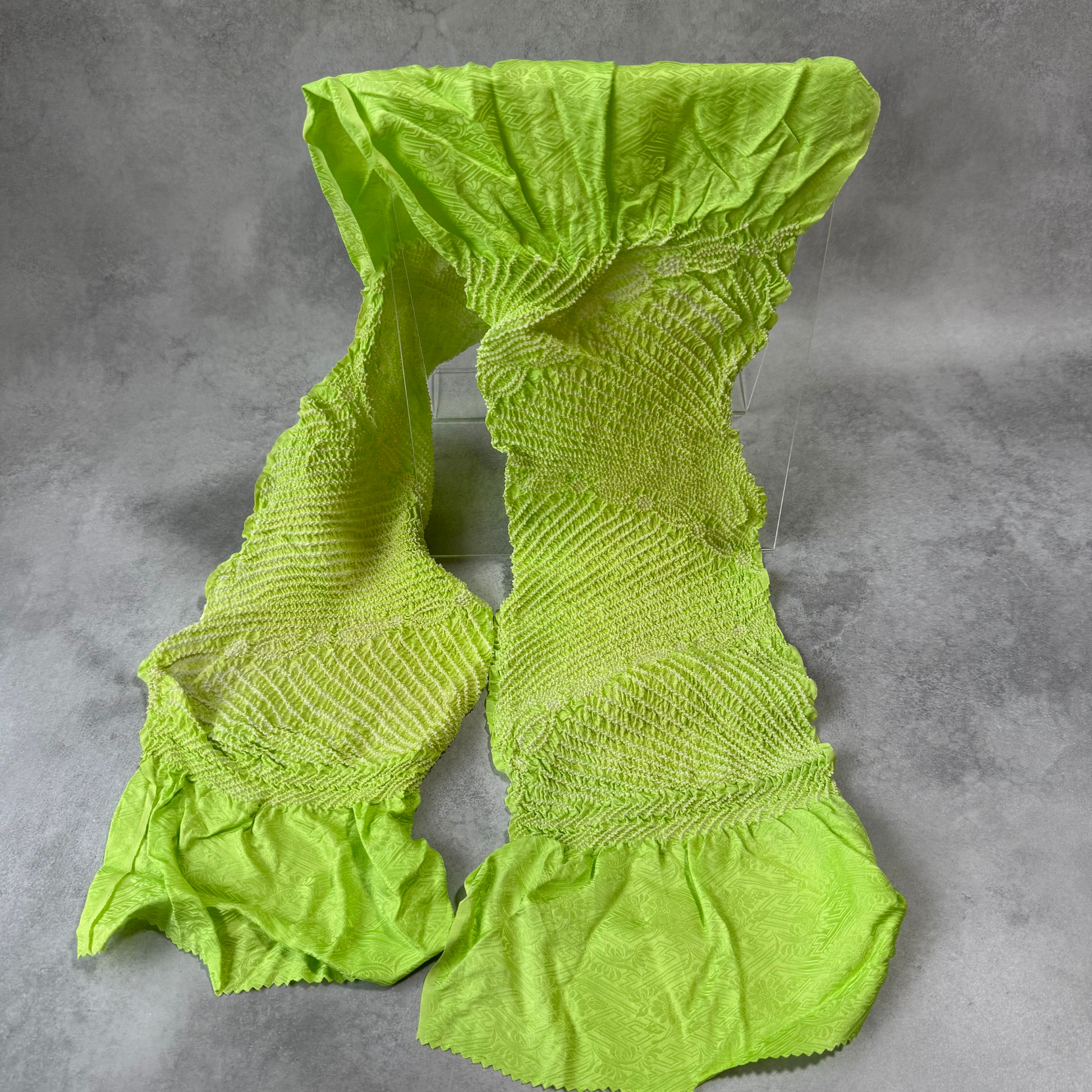 Full view of a vintage Japanese silk shibori obiage in vivid lime green with white floral motifs