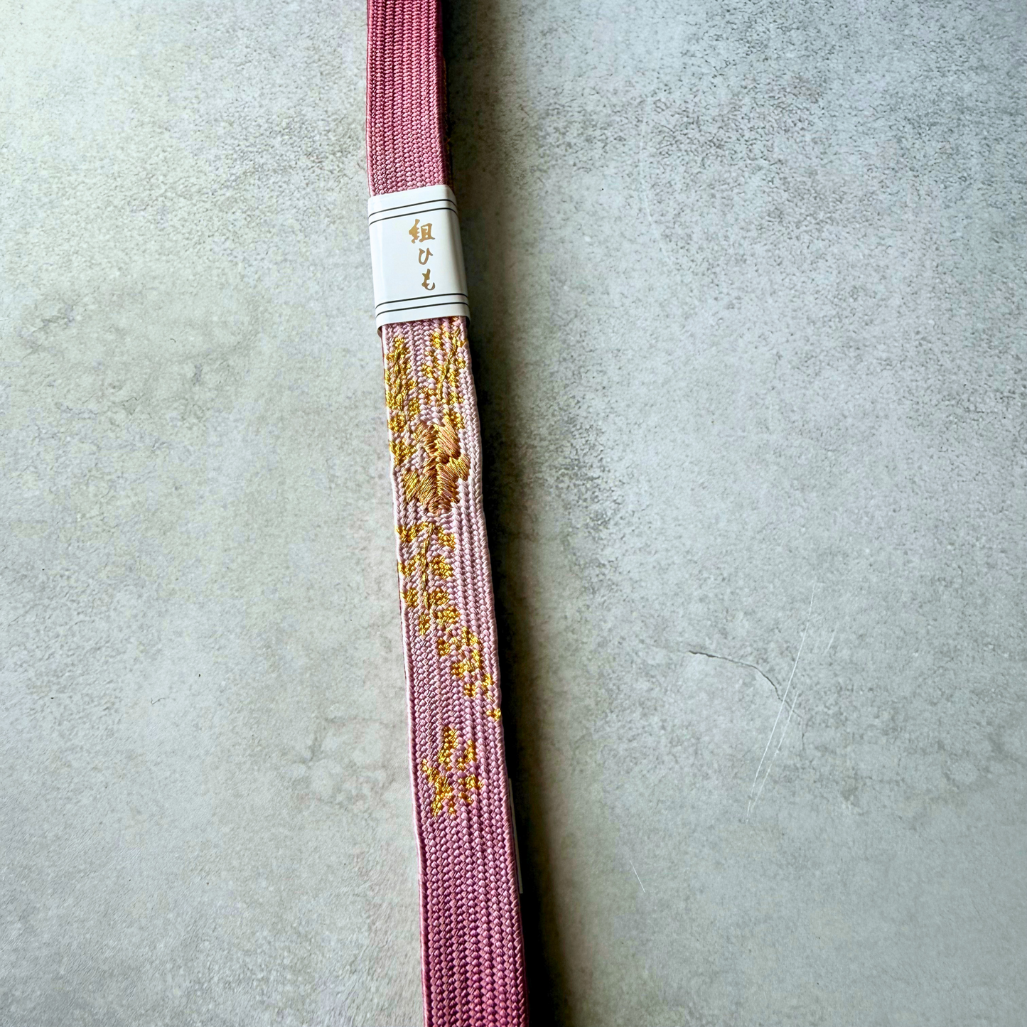 Close-up of the dusty pink Korai-gumi silk obijime with gold floral-inspired decorative motifs