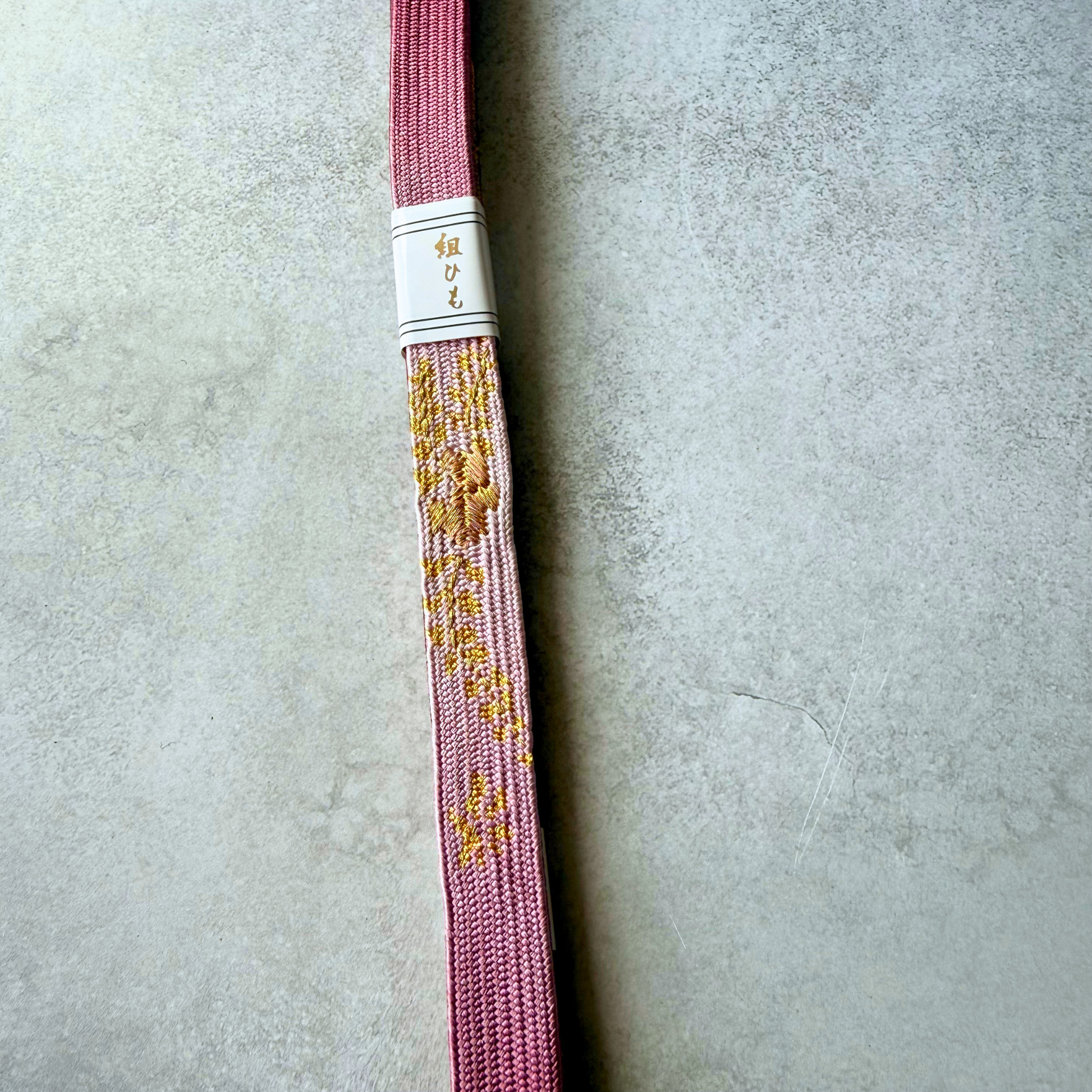 Close-up of the dusty pink Korai-gumi silk obijime with gold floral-inspired decorative motifs