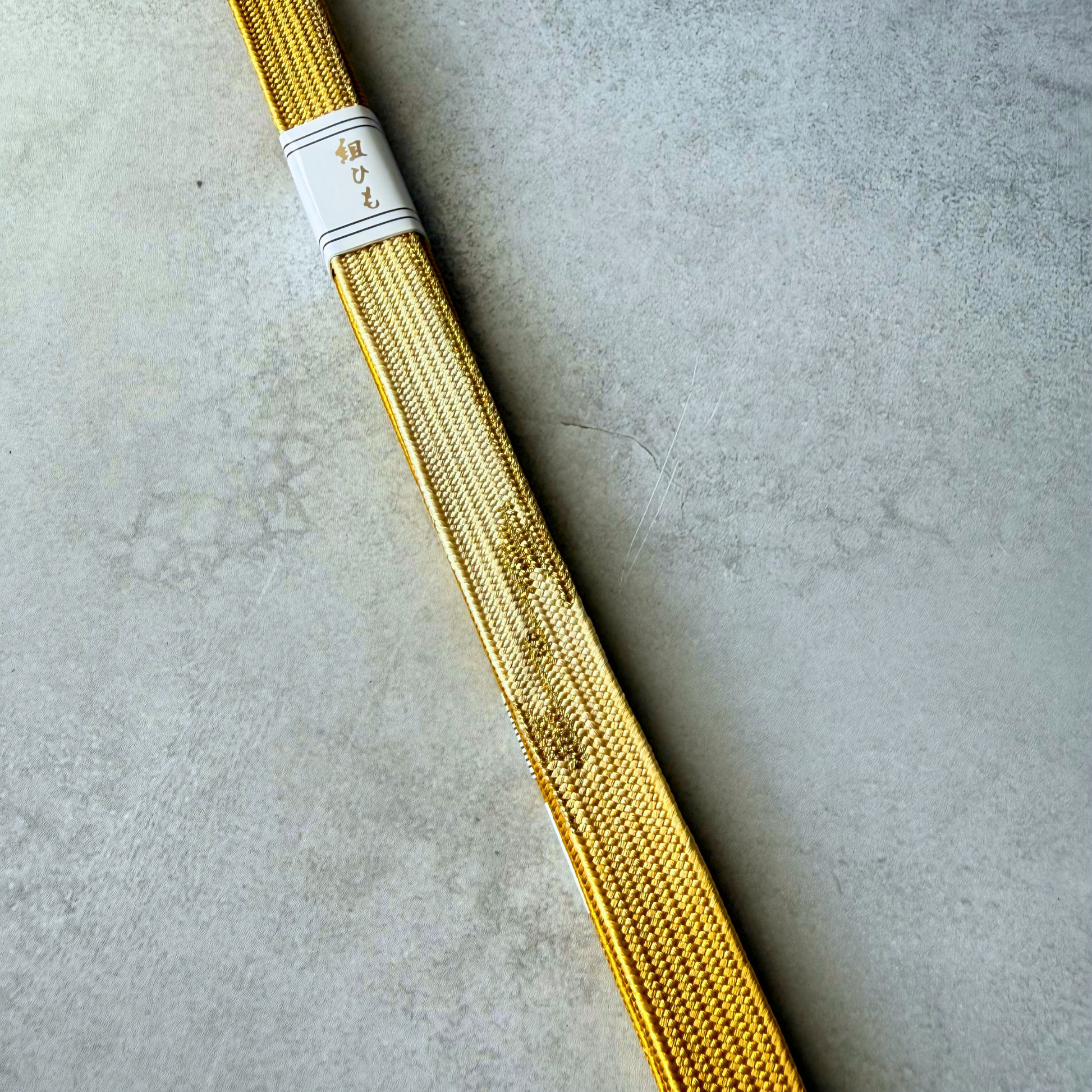 Close-up of the metallic gold decorative woven motif on the hand-braided silk obijime