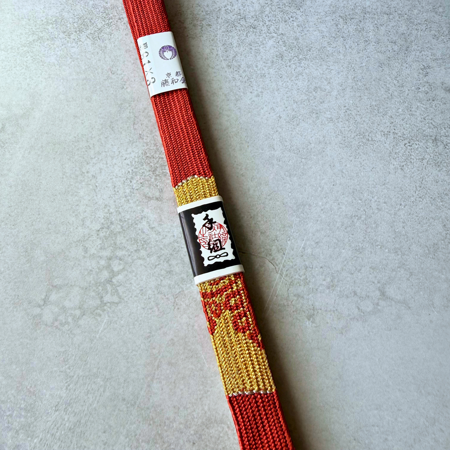 Close-up of the metallic gold decorative woven motif on the crimson red Korai-gumi silk obijime