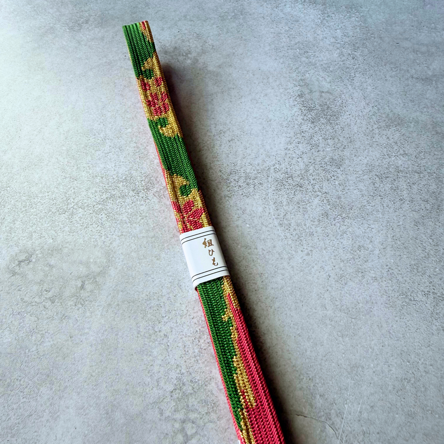Close-up of deep green Japanese silk Korai-gumi obijime with crimson and gold floral motifs