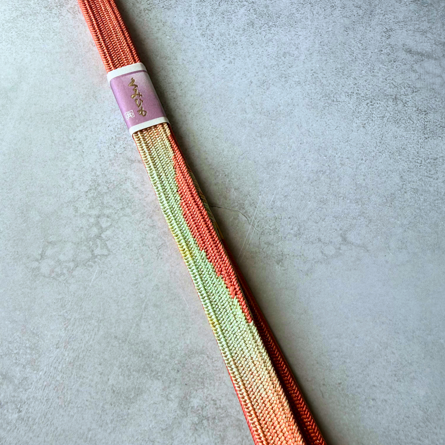 Close-up of pale green, gold and vermilion geometric pattern on hand-braided silk Korai-gumi obijime