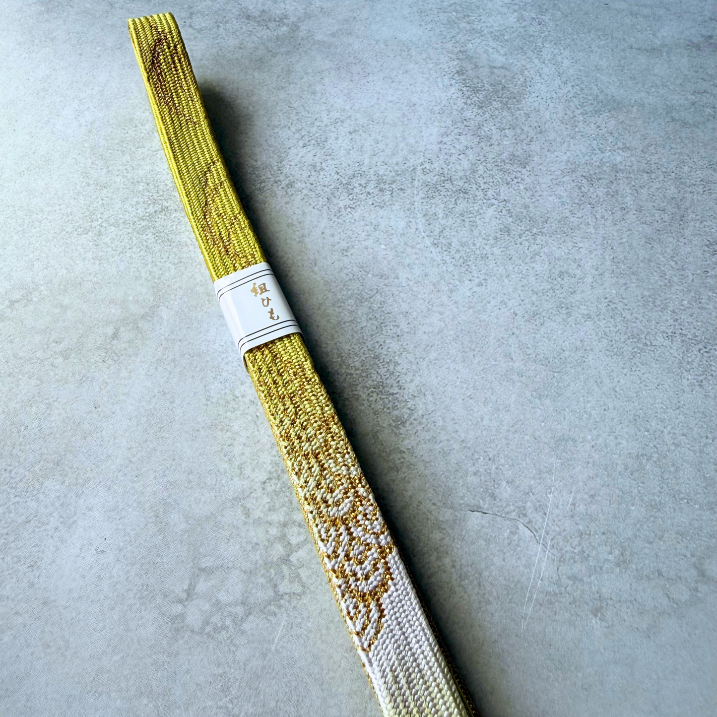 Close-up of white and metallic gold decorative woven motifs on the silk obijime