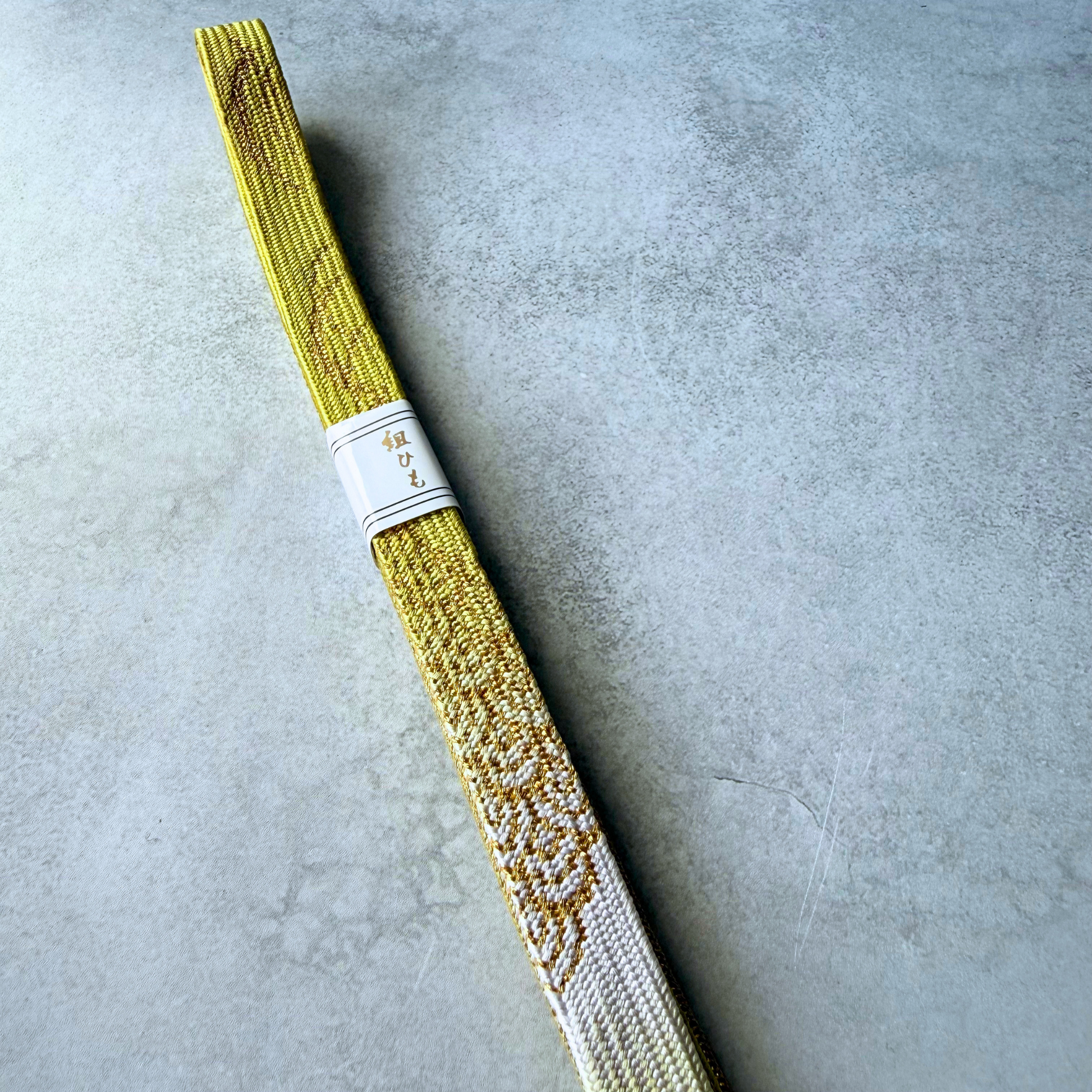Close-up of white and metallic gold decorative woven motifs on the silk obijime