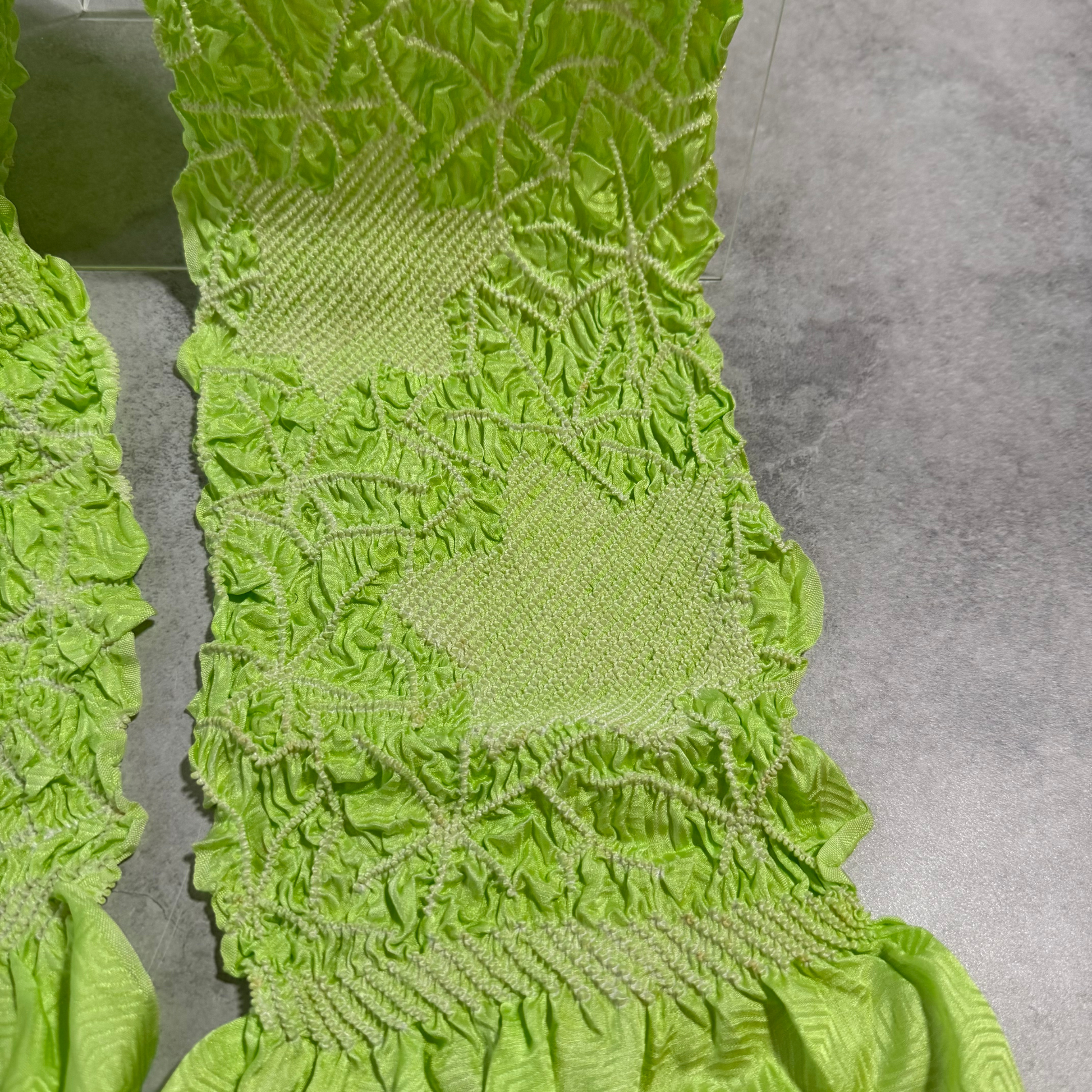 Close-up of pale diamond panels and curved shibori motifs on lime green silk obiage