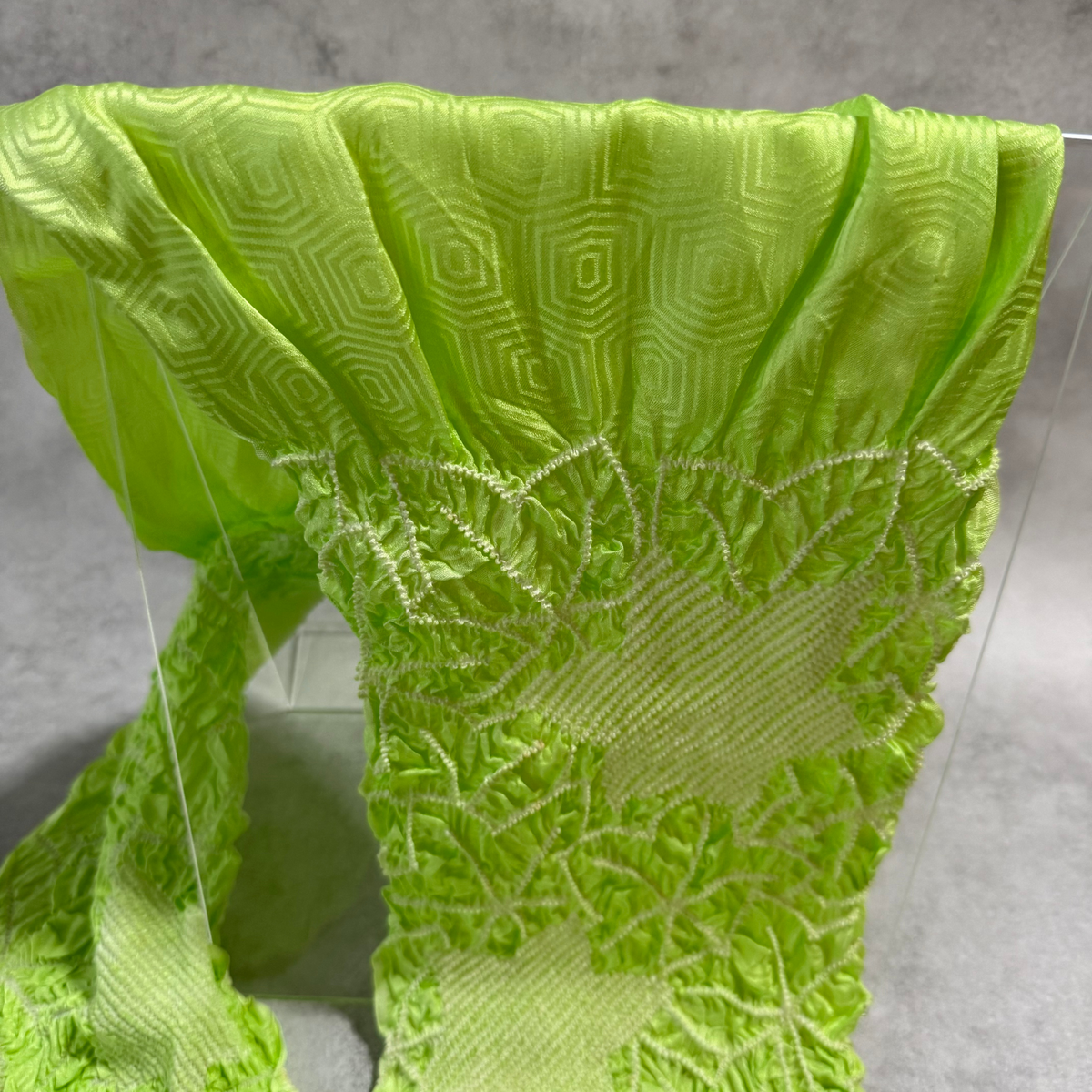 Close-up of woven geometric ground and textured shibori on lime green Japanese silk obiage