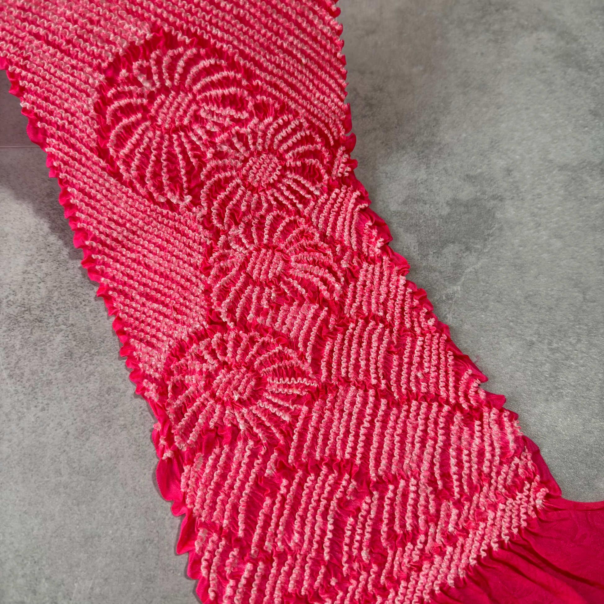 Close-up of circular floral shibori motifs on a vivid magenta silk obiage