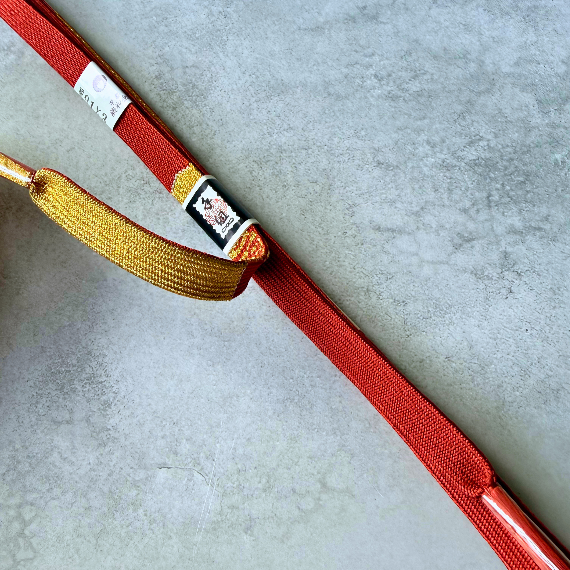 Detailed view of the metallic gold and crimson red hand-braided silk structure