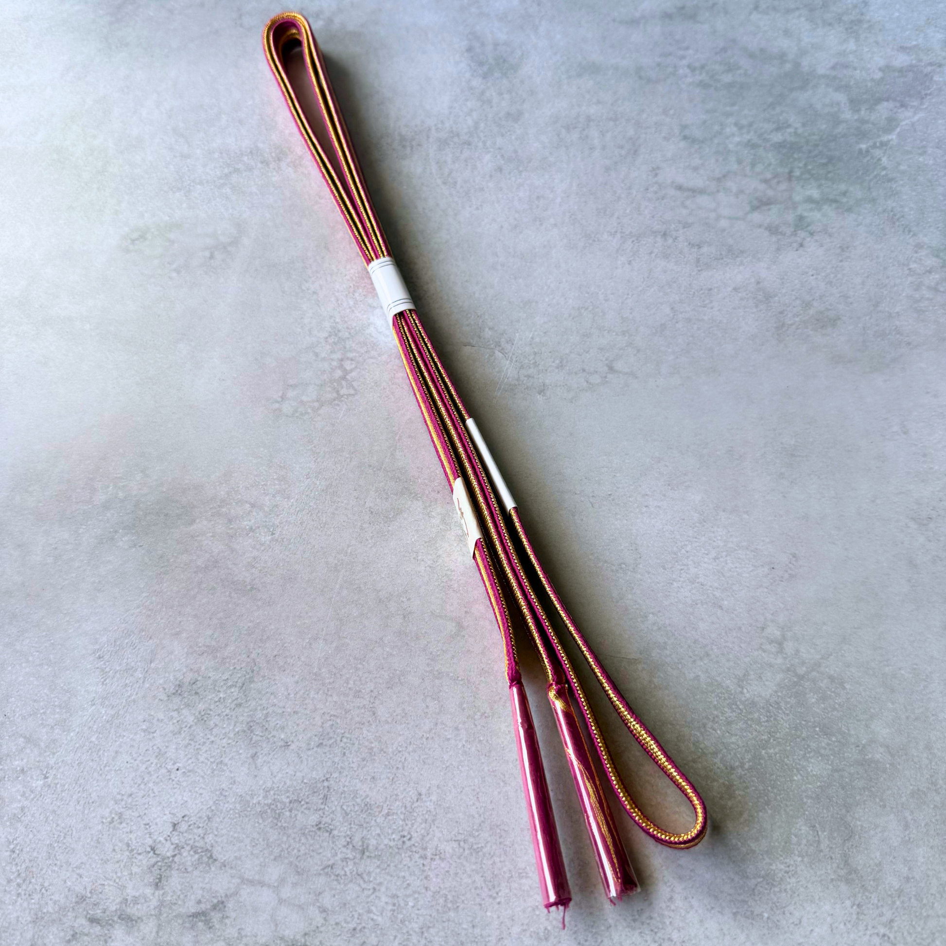 Both sides and tasselled ends of the magenta pink and metallic gold Japanese silk obijime