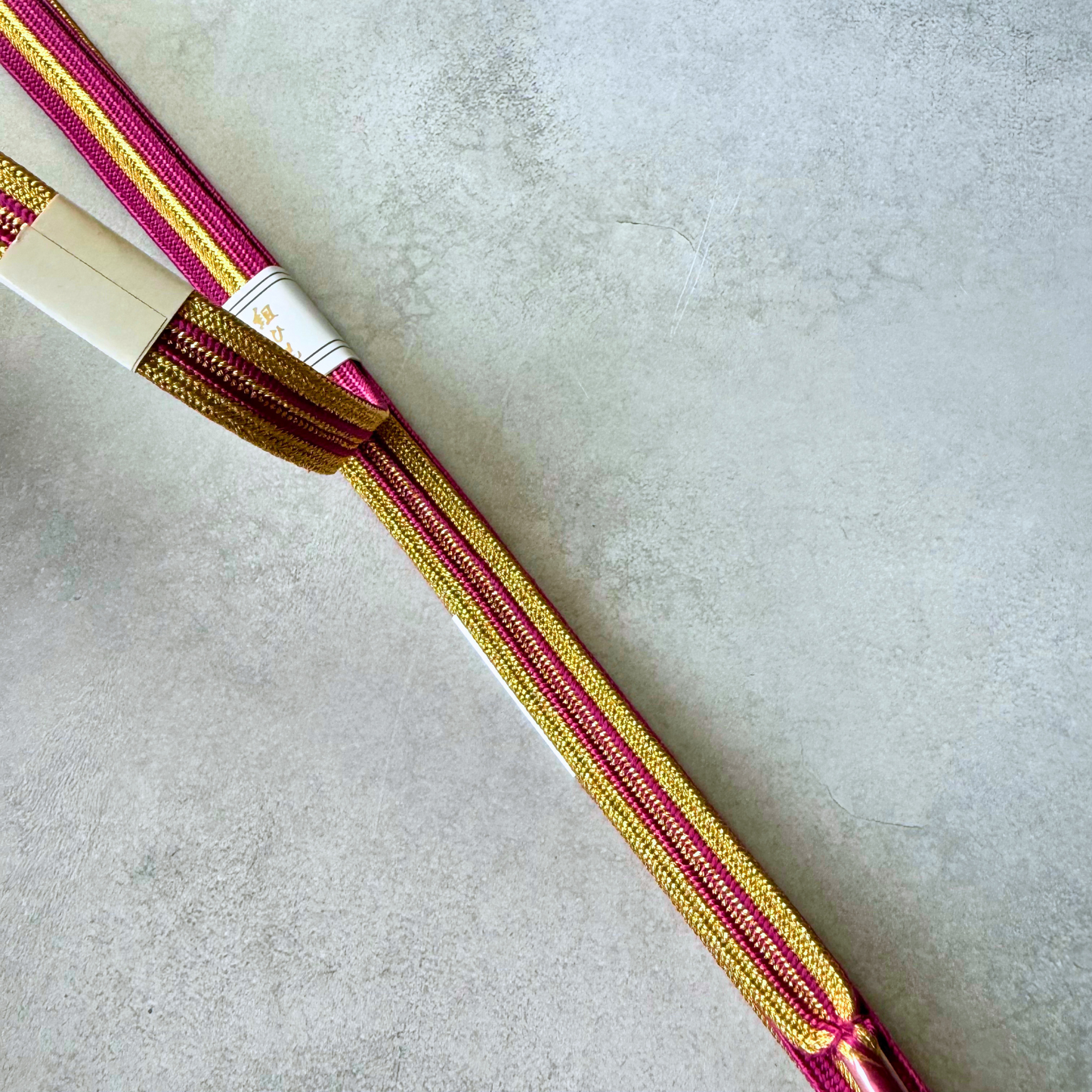 Close-up comparison of the metallic gold and magenta pink sides of the hand-braided Korai-gumi obijime