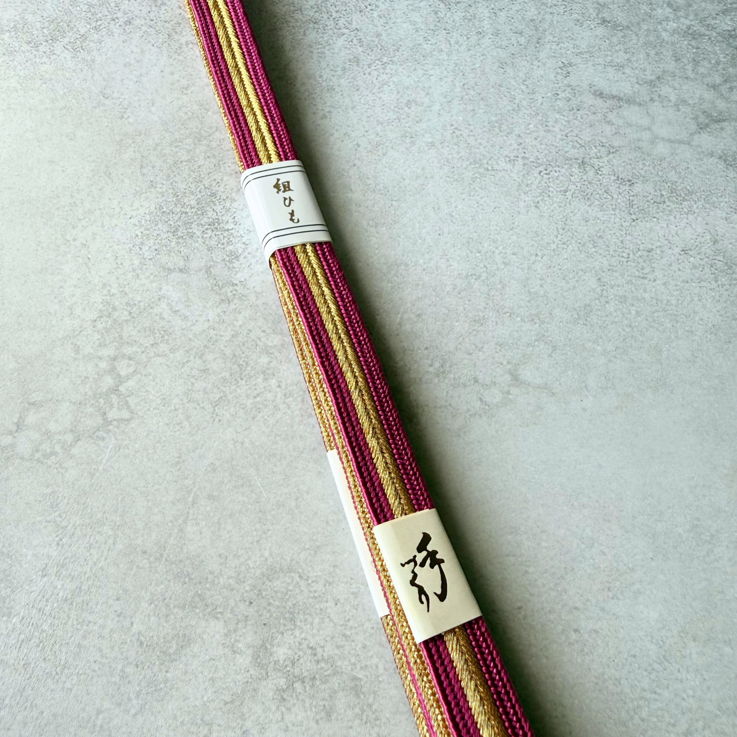 Close-up of the magenta pink and metallic gold hand-braided silk texture of the Japanese obijime