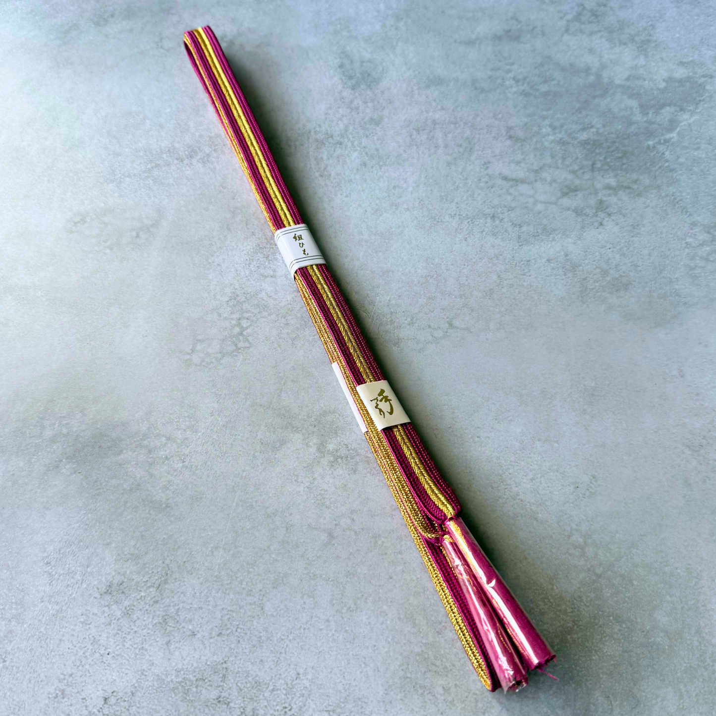 Full view of an unused Japanese silk Korai-gumi obijime in magenta pink and metallic gold