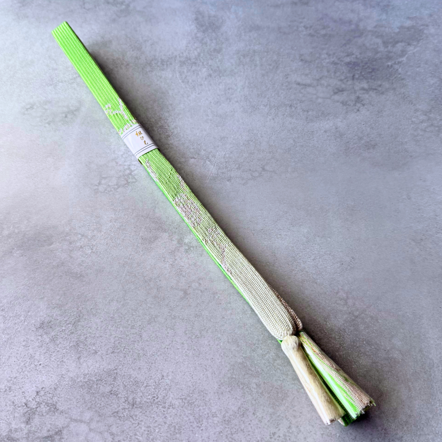 Unused Japanese silk Korai-gumi obijime in vivid lime green, ivory and pale gold with flowing decorative motifs