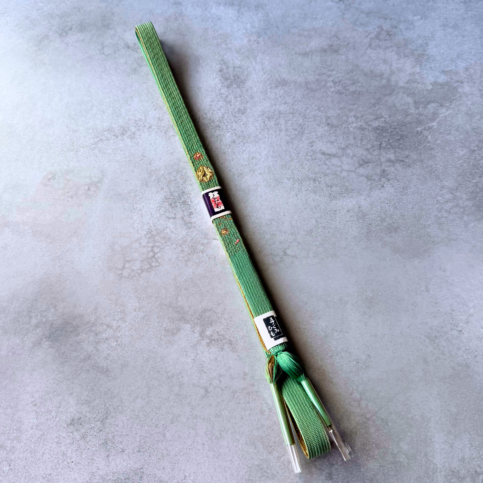 Full view of celadon green Japanese silk Korai-gumi obijime with gold and pink woven motifs