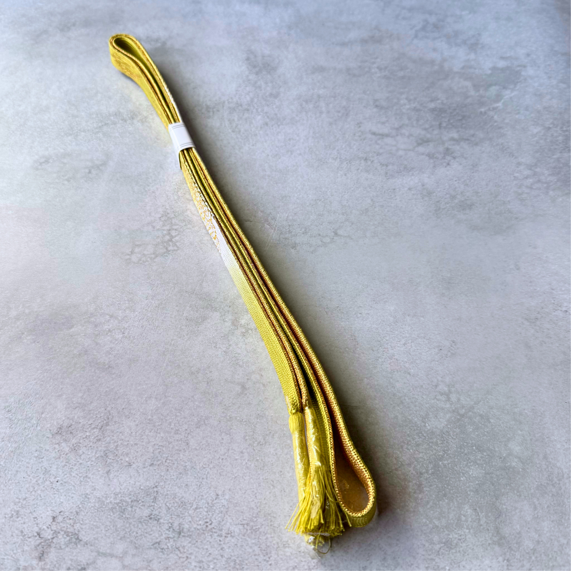 Both sides and tasselled ends of the olive yellow and gold Japanese silk obijime