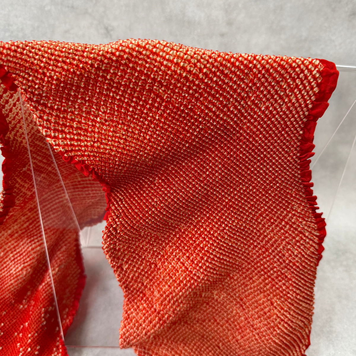 Macro view of fine ivory kanoko-style shibori dots on vermilion red silk