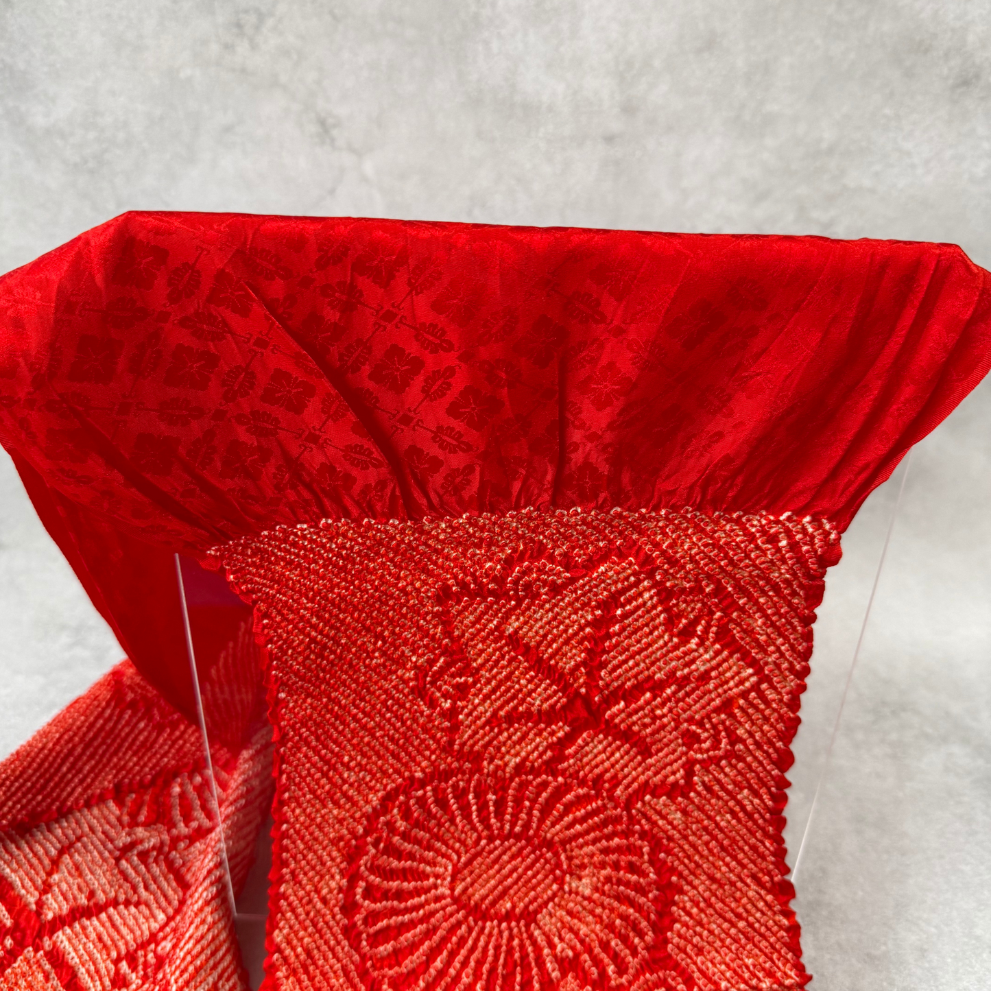 Close-up of woven floral texture and shibori section on red Japanese silk obiage