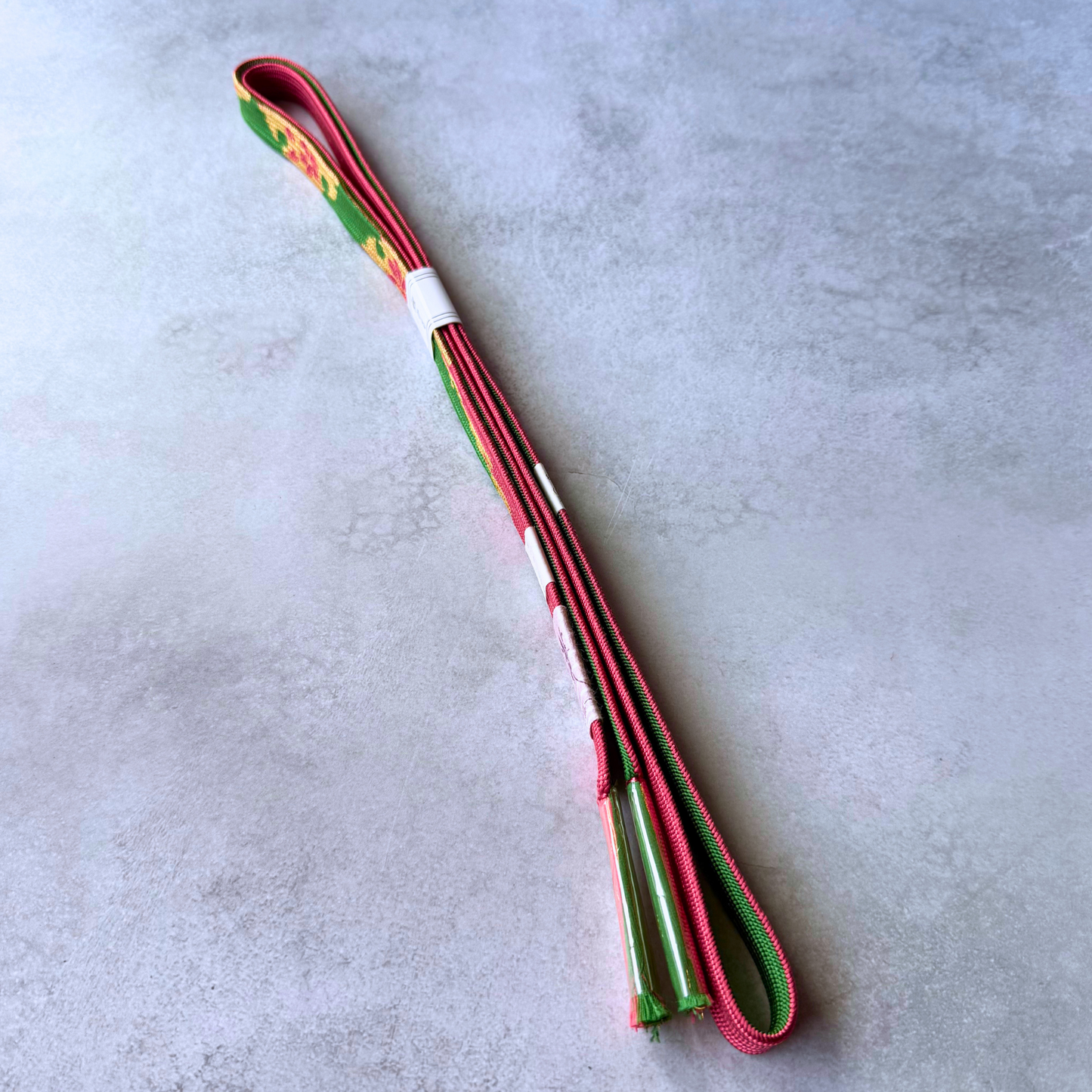 Reversible green and crimson Japanese silk obijime showing both sides and protected tassels