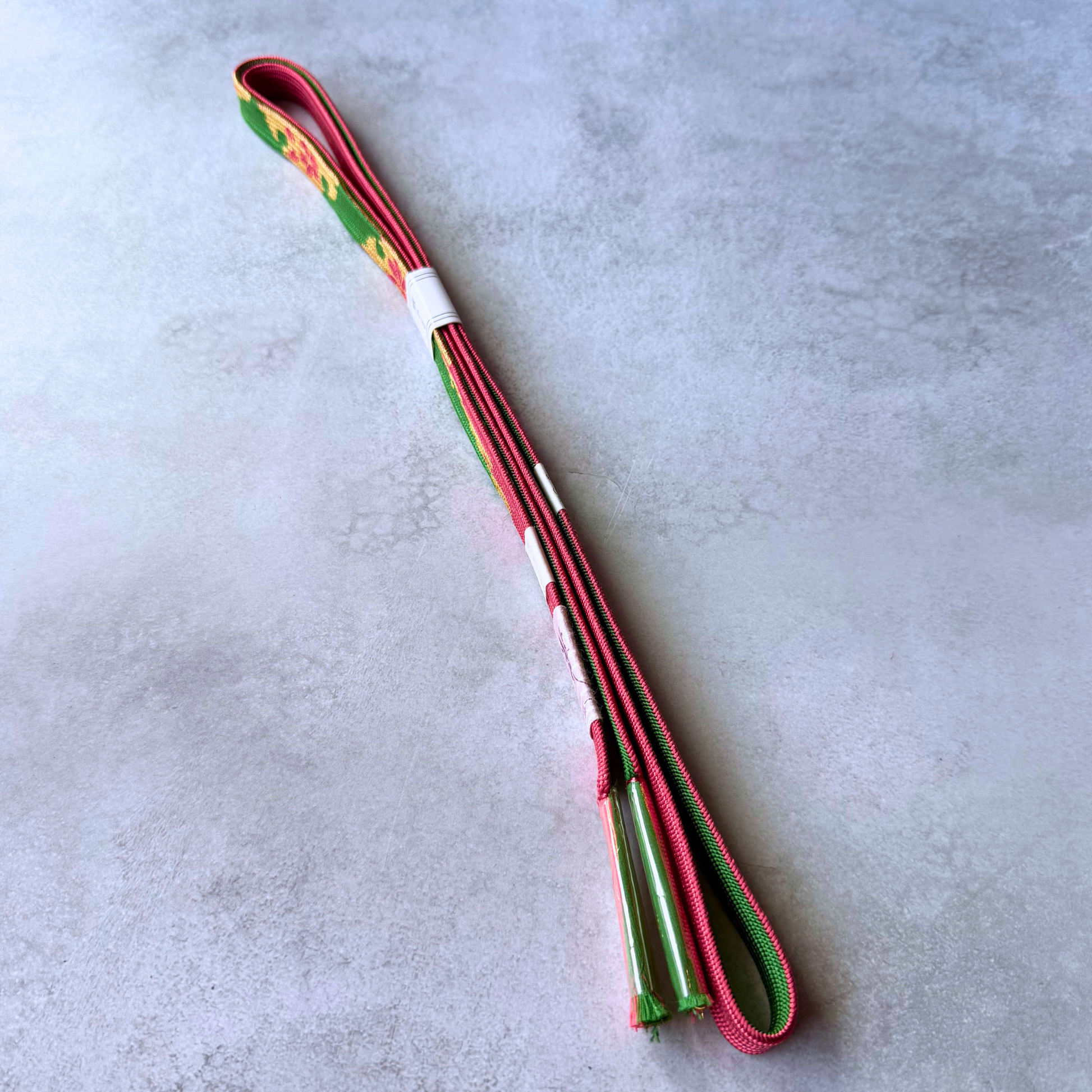 Reversible green and crimson Japanese silk obijime showing both sides and protected tassels