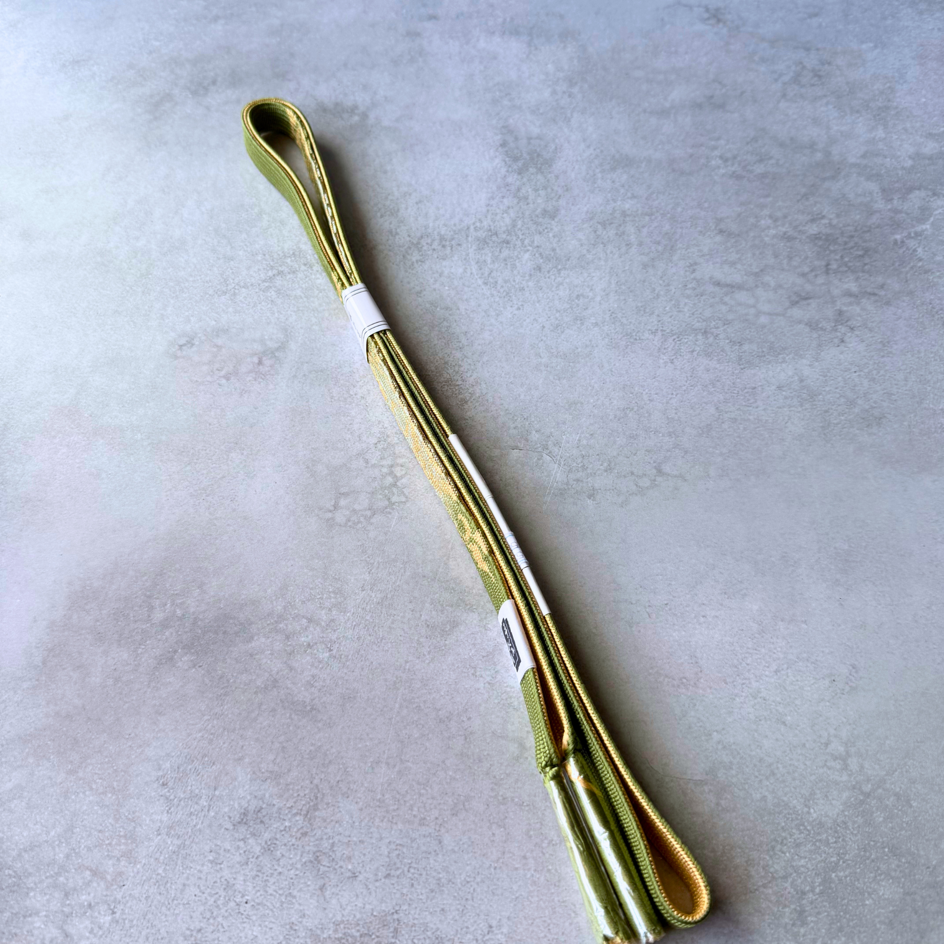 Reversible Japanese silk obijime showing olive green and gold braided sides