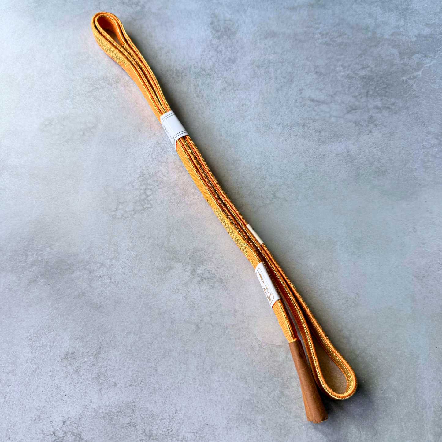 Both sides and tassel ends of a reversible orange and gold Japanese silk obijime cord
