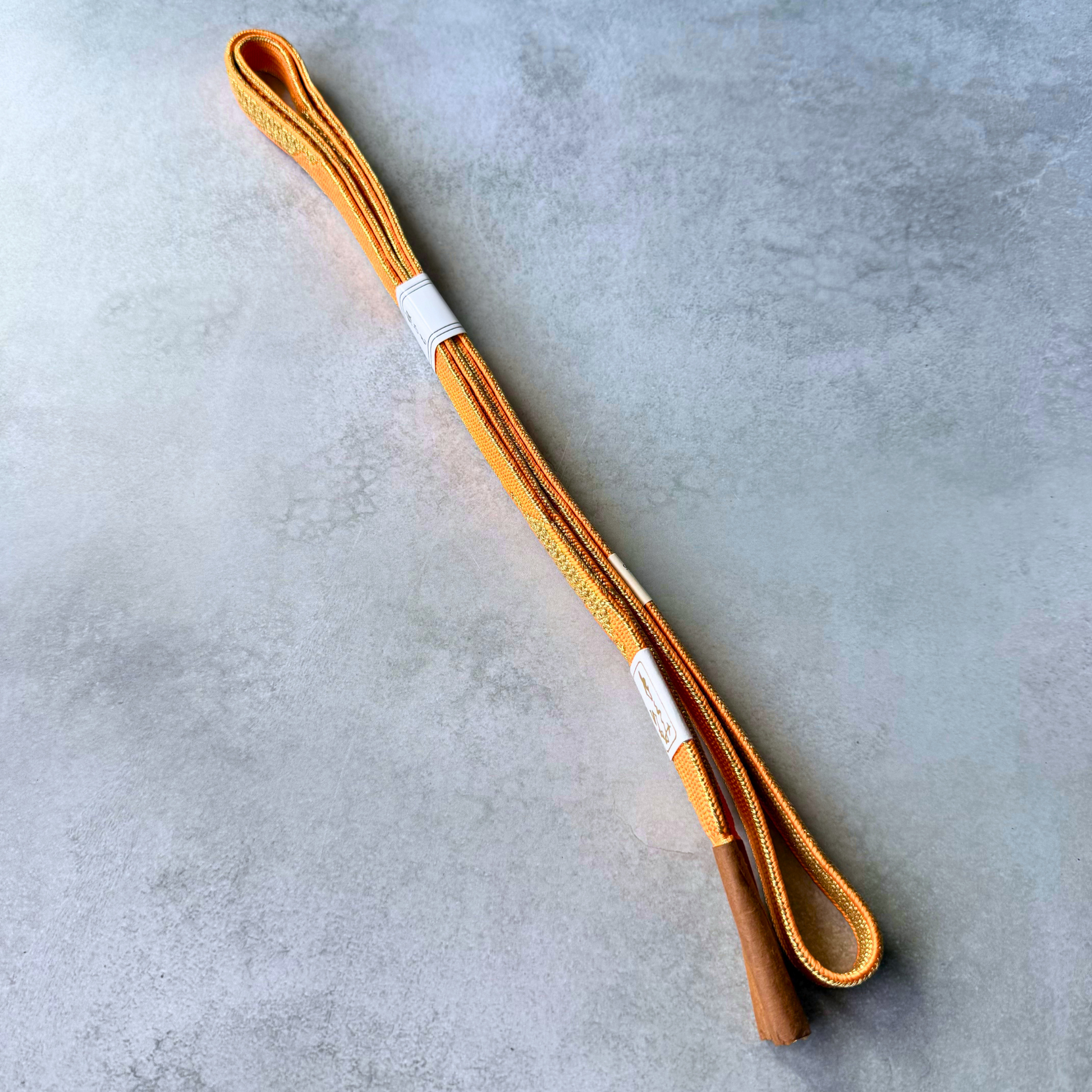 Both sides and tassel ends of a reversible orange and gold Japanese silk obijime cord