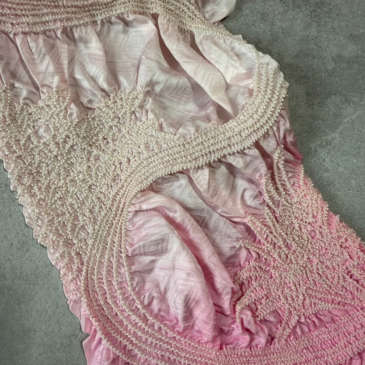 Macro view of the shibori texture and geometric woven design on pink silk