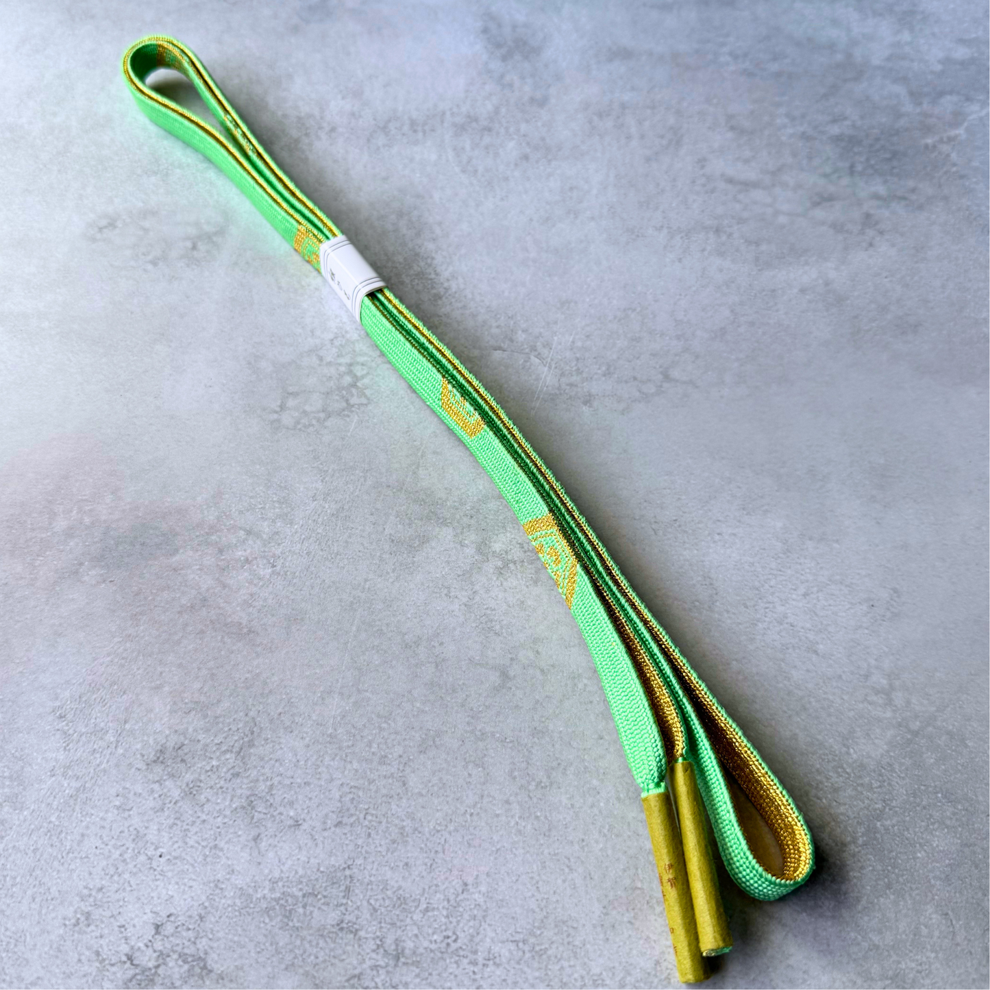 Both sides and tassel ends of a bright spring green and gold Japanese silk obijime cord