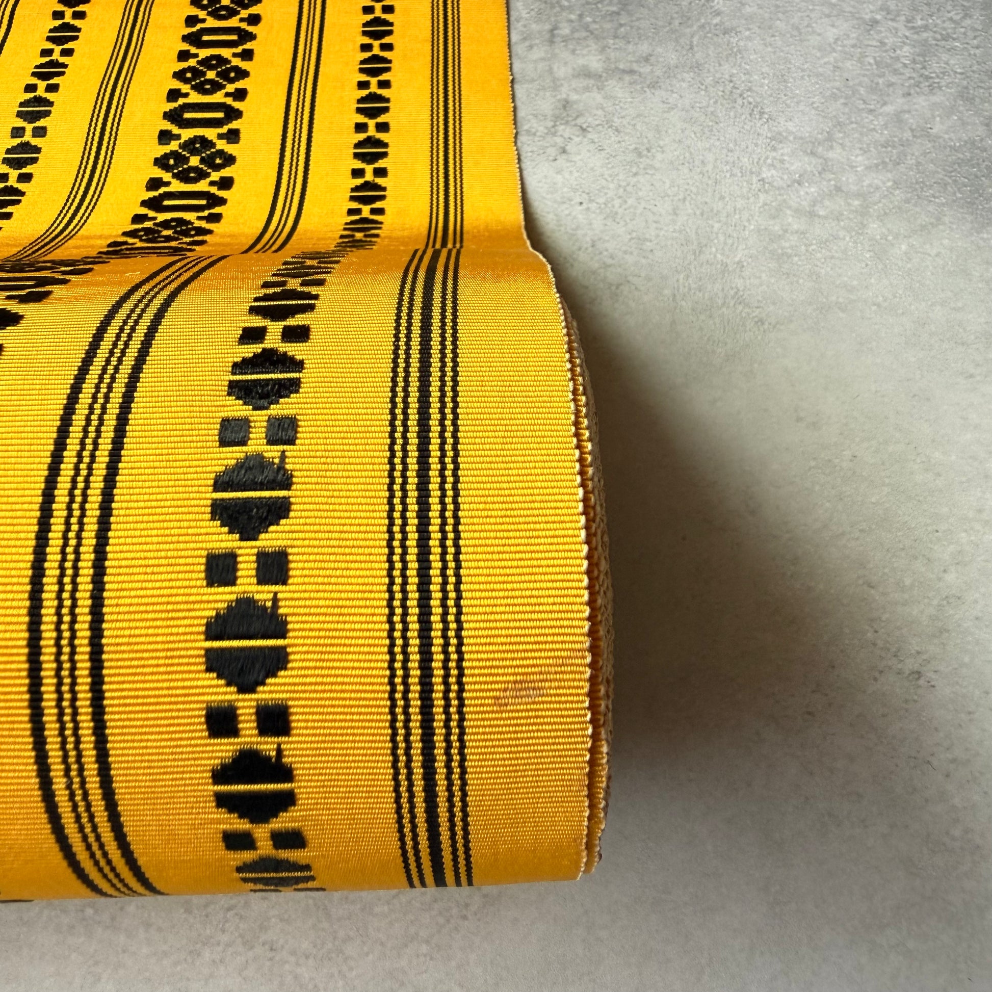 Detail of black geometric motif and stripes on yellow obi textile